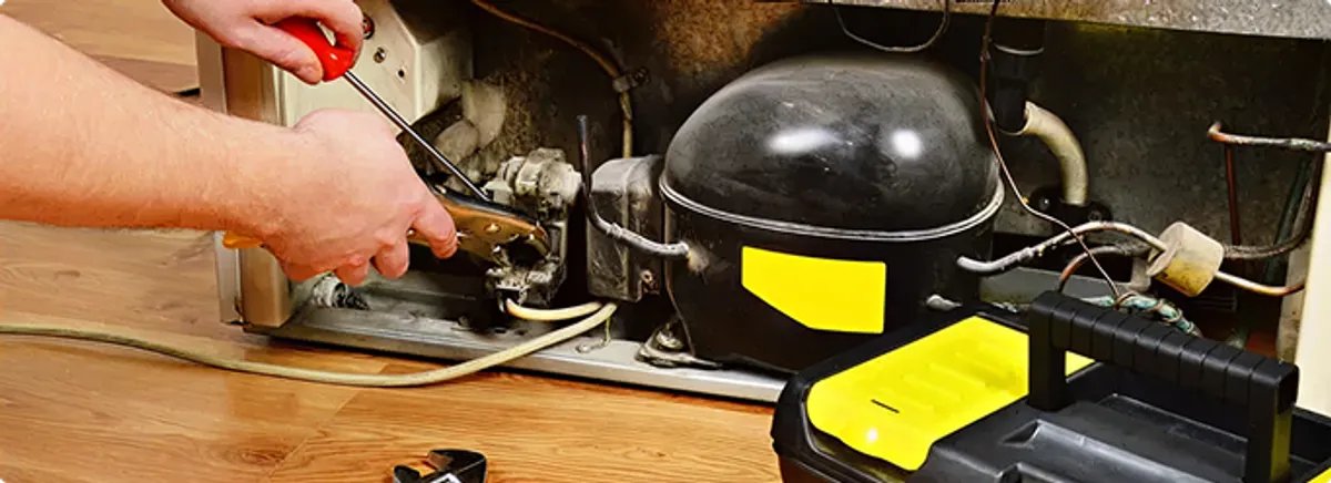 Refrigerator repair technician fixing the compressor and wiring in Newcastle, OK