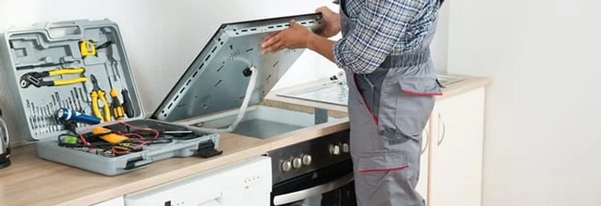 Cooktop repair technician lifting a built-in stovetop for service in Oklahoma City, OK