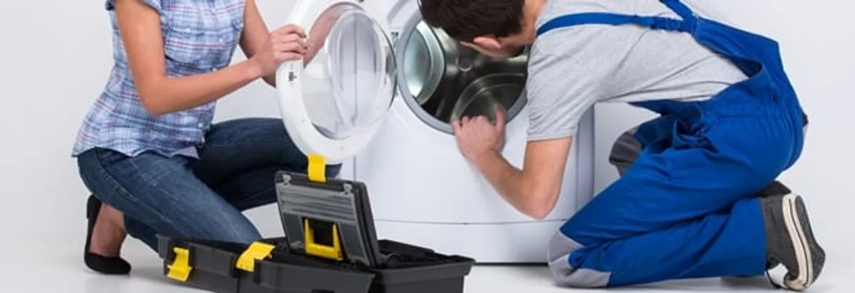 Washer repair technician inspecting a front-load washing machine with tools in Oklahoma City, OK