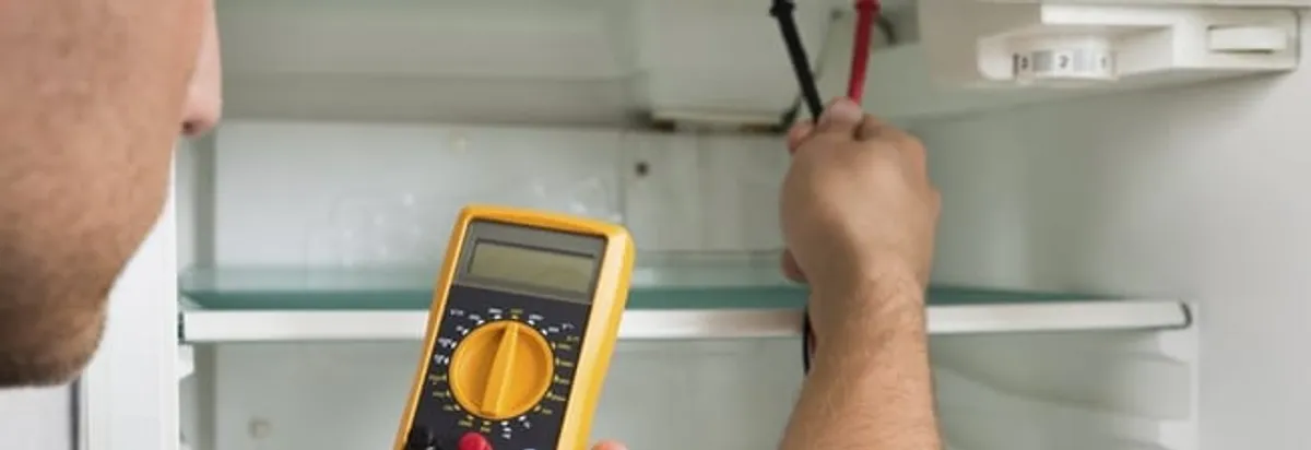 Refrigerator repair technician testing electrical components with a multimeter in Oklahoma City, OK
